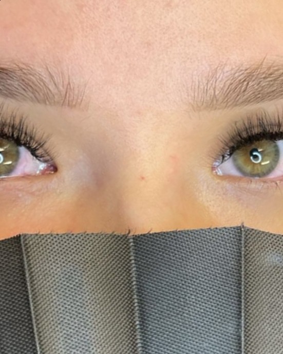 Close-up van wimperextensions, klant met een waaier voor het gezicht